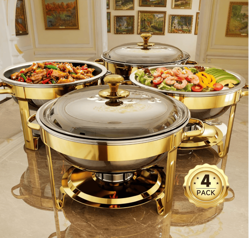 Three elegant gold-trimmed chafing dishes filled with vibrant dishes, including a stir-fry, a salad with shrimp, and assorted vegetables, displayed on a marble surface in a stylish interior setting.