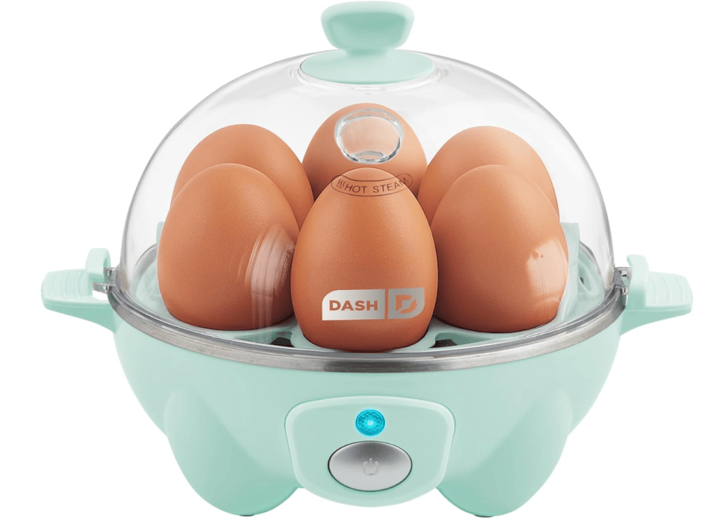A light blue egg cooker with a transparent cover containing six brown eggs, featuring a power button with a blue indicator light.